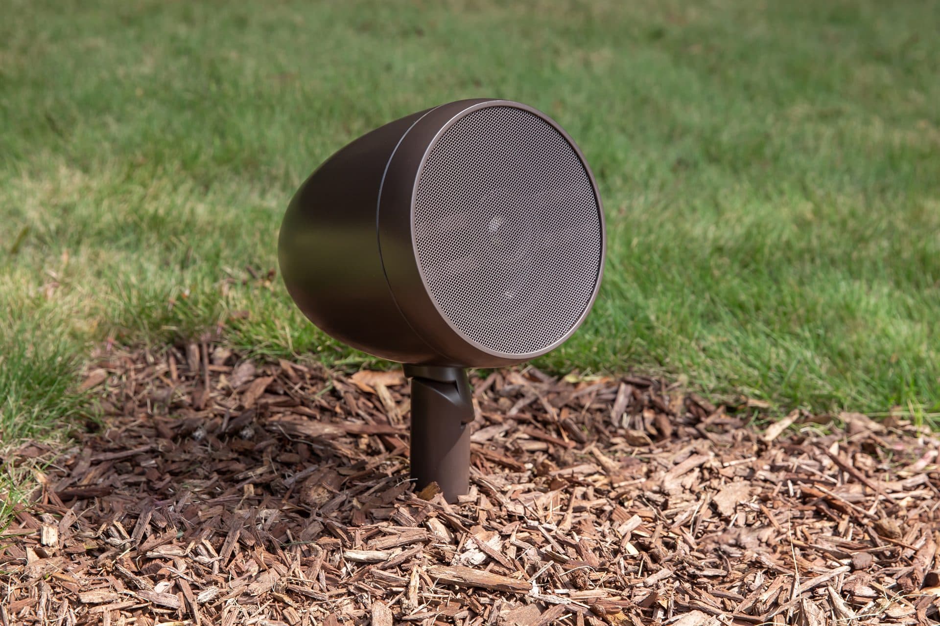 A discreet bronze outdoor speaker set into a garden border