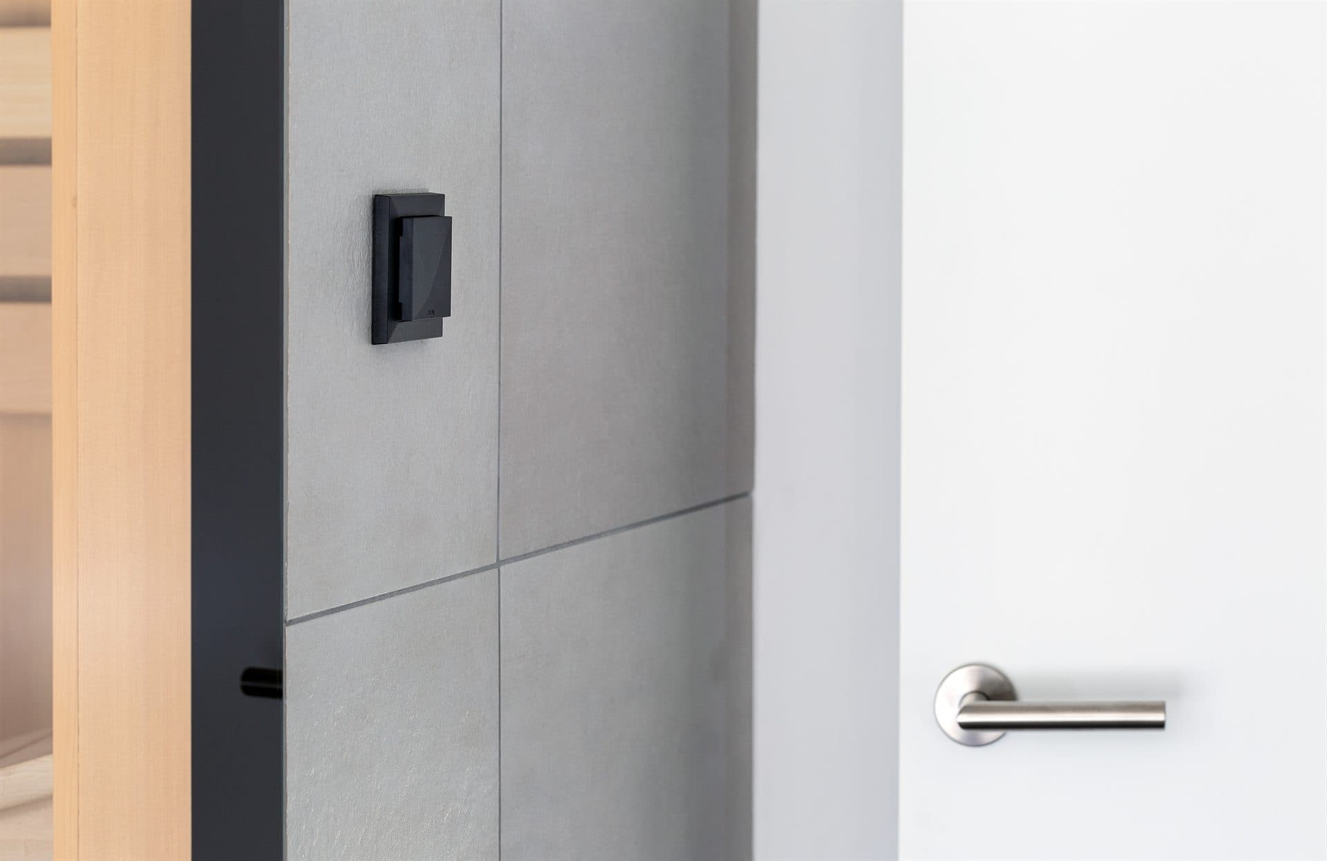 A discreet Loxone room comfort sensor beside a door in a modern home