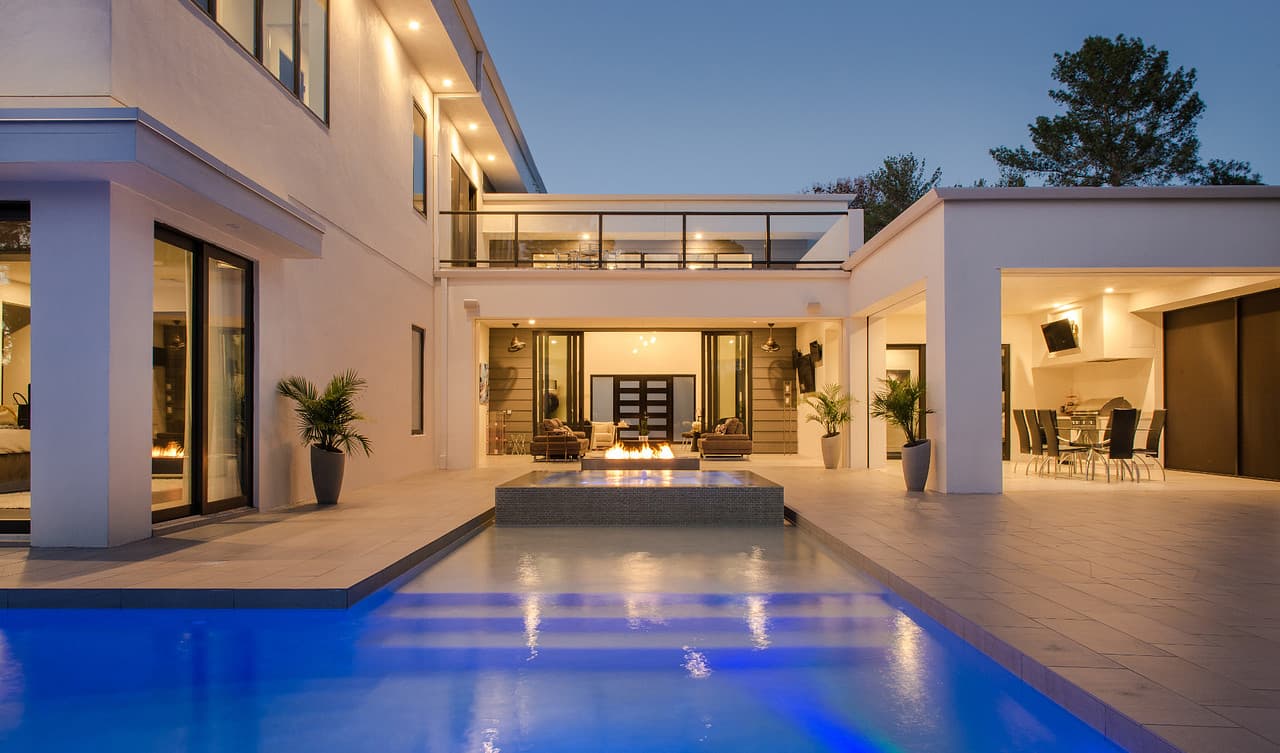 A luxury home at dusk with integrated lighting and an illuminated infinity pool