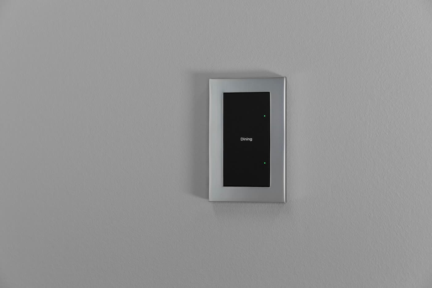 A minimal satin nickel light switch on a plaster wall