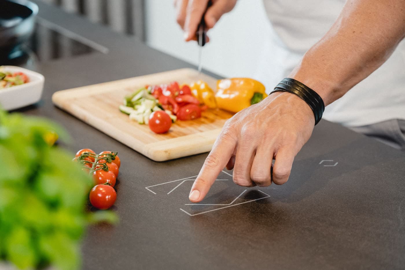Someone cooking and adjusting a nearby touch control in the kitchen