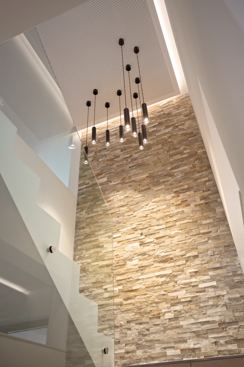 A linear pendant light over a dining setting at low brightness