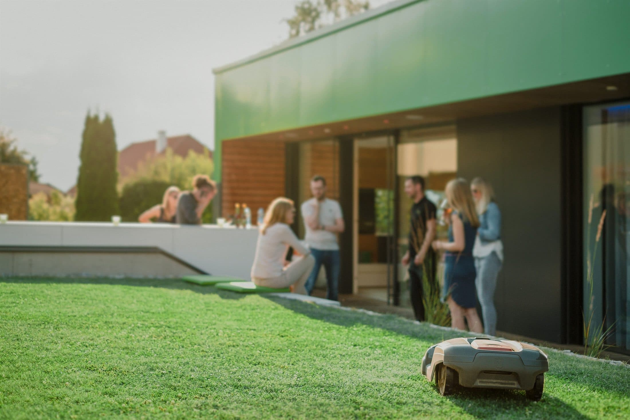 Friends gathering in a garden at golden hour outside a modern automated home