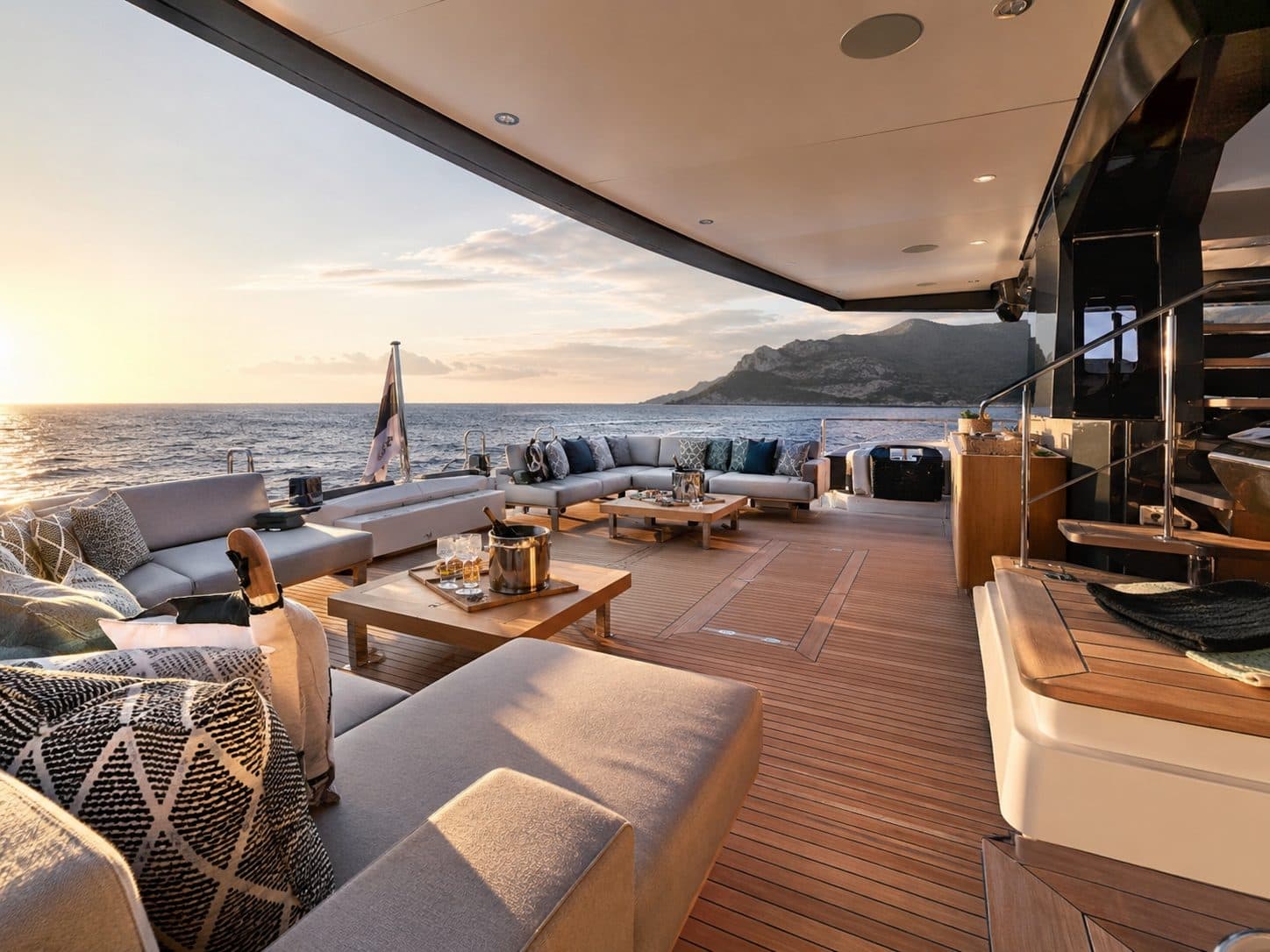A yacht aft-deck lounge at sunset with built-in seating